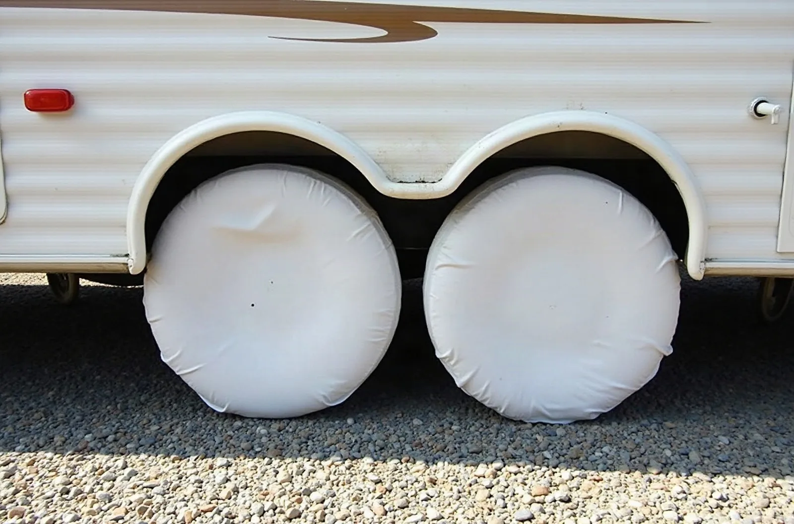 White tire covers on RV wheels protect tires from sun damage during outdoor RV storage.