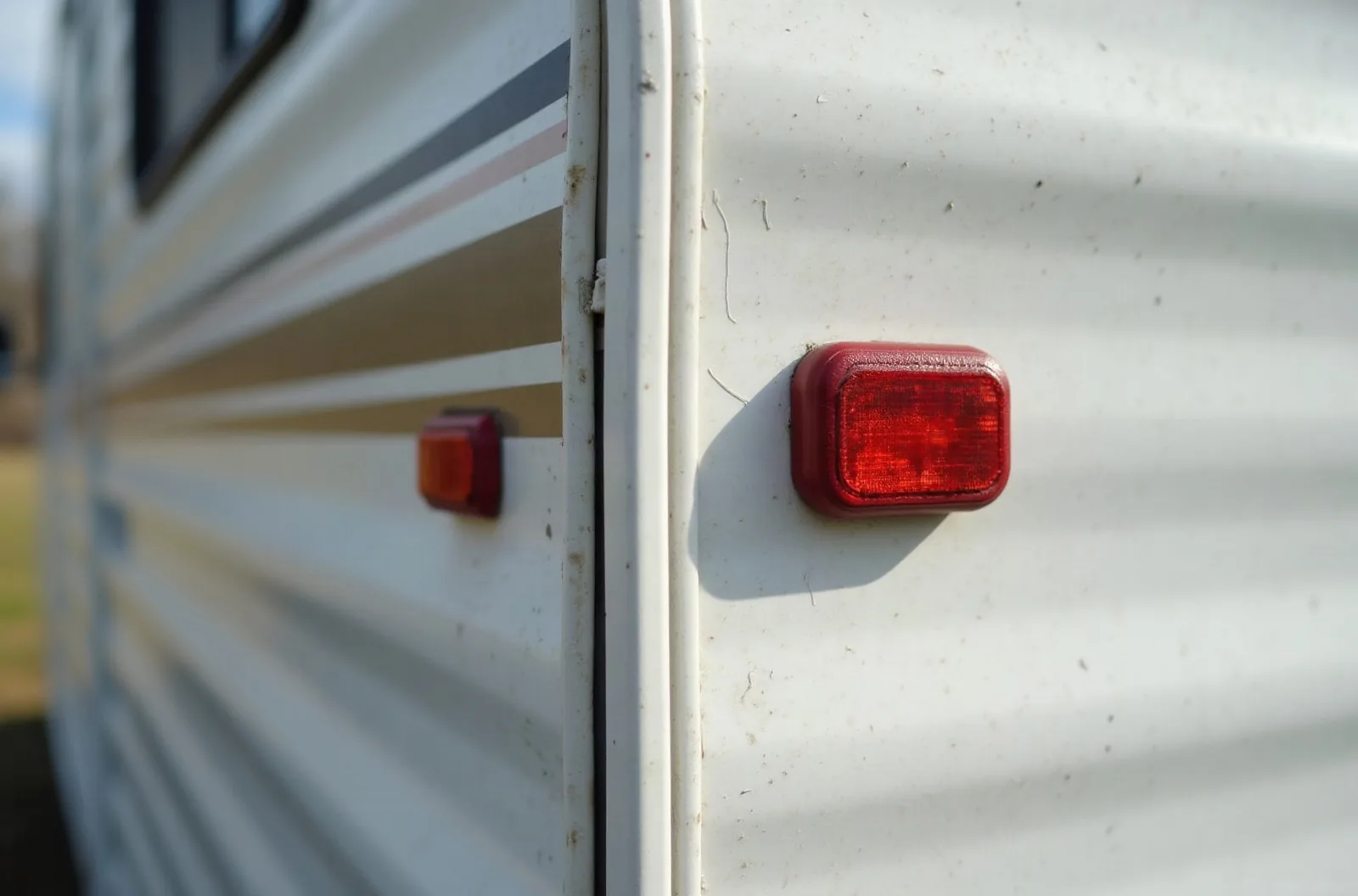 Close-up of RV storage cover strap buckle and padded corner on a travel trailer